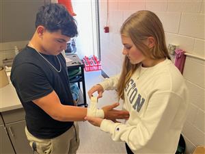 Sports Medicine student taping wrist of student athlete