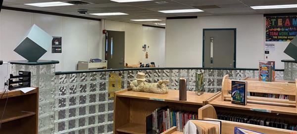 Wide view of a white wall with several doors with media center books in the foreground